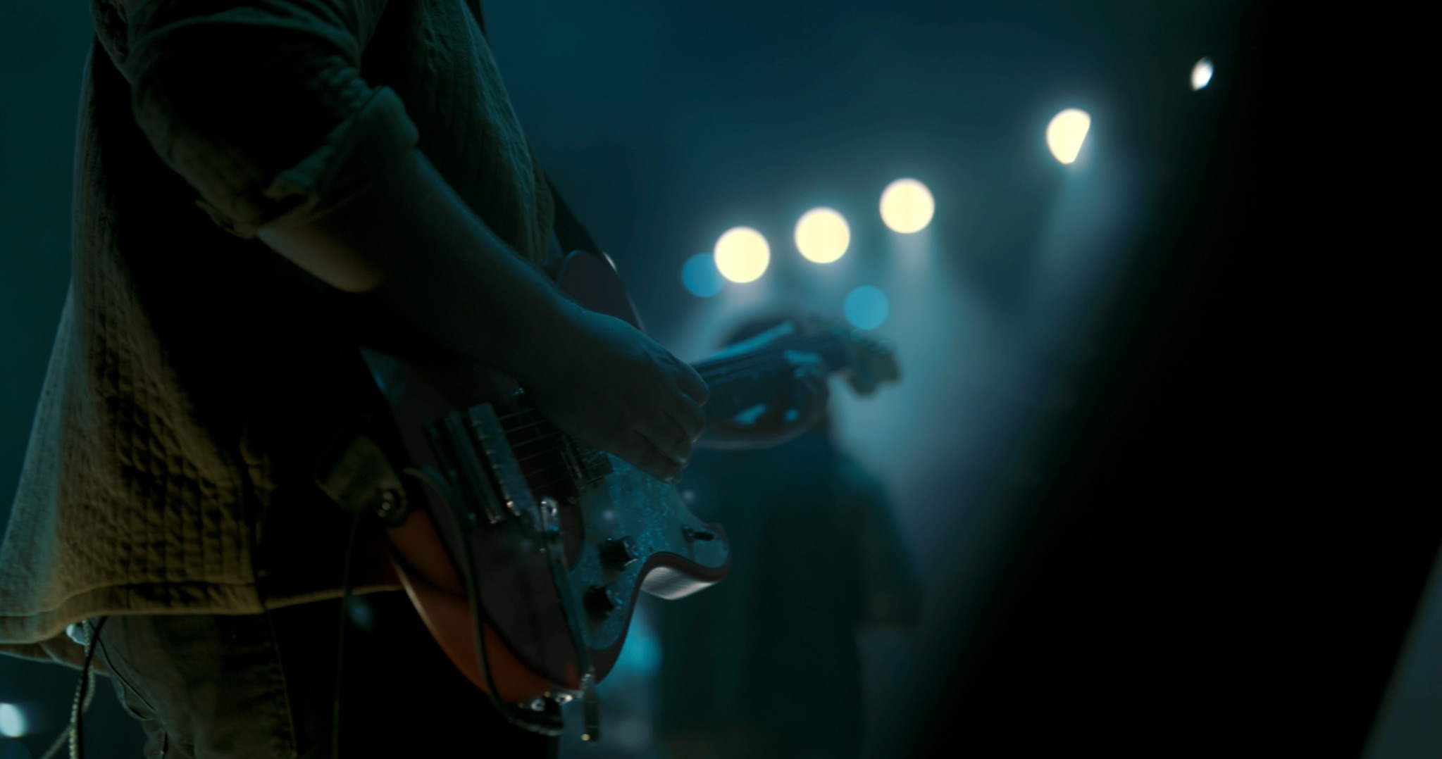 Guitarist performing under blue stage lighting